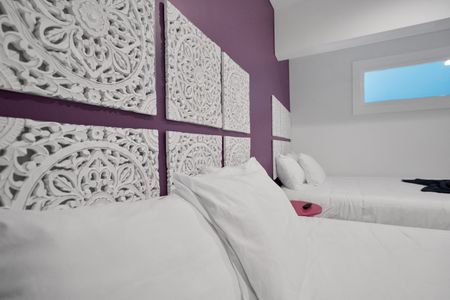 Bedroom 2 w/ a bold purple headboard wall & crisp white linens for a dramatic retreat.