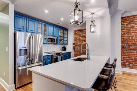 Sleek kitchen w/ stainless steel appliances & bold blue cabinetry.