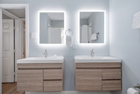 Freshen up at the double vanity w/ lit mirrors & clean, modern finishes.