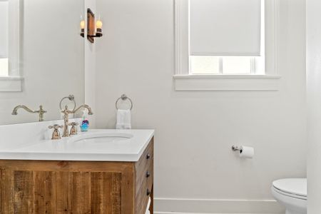 First bathroom vanity w/ sink & large mirror.