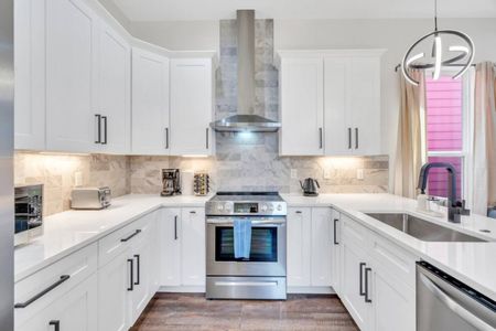 Fully stocked kitchen w/ stainless appliances & sleek white cabinetry.