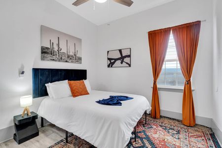 Bright bedroom w/ crisp white walls, teal curtains, & a bold orange headboard.