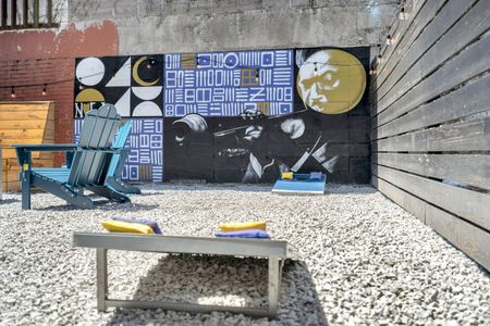 Backyard cornhole & bold mural backdrop — where good times happen naturally.