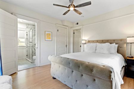 Soft, airy bedroom w/ natural light pouring in through large windows.