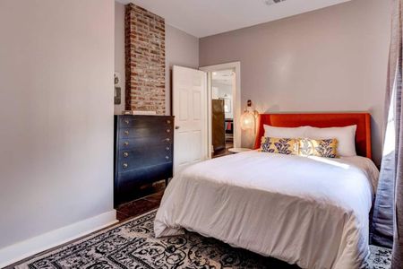Cozy bedroom w/ warm red curtains & a welcoming bed.