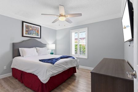 Airy bedroom w/ ceiling fan & soft natural light for restful nights.