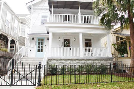 Classic two-story home exterior w/ wraparound balcony & iron fence.