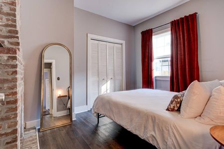 Sun-drenched bedroom w/ arched mirror & shuttered windows for a breezy feel.