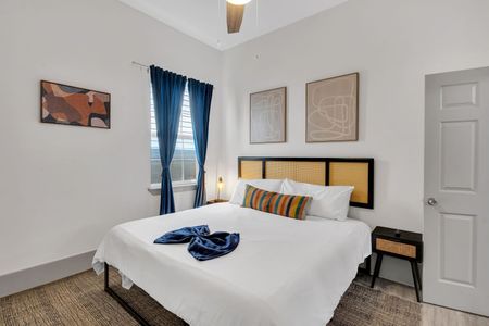 Cozy bedroom w/ bold teal curtains, layered bedding, & warm wood accents for restful nights.