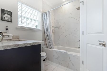 Private ensuite bath w/ marble-finish walls & a toilet — shower just off to the right.