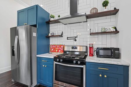 Sleek kitchen corner w/ a gas range, teal cabinets & classic white subway tile backsplash.