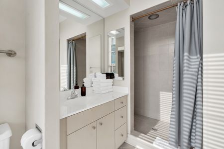 Bright, tiled bathroom w/ a clean sink vanity & mirror.