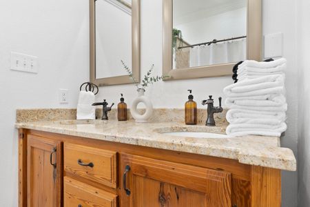 Double-sink vanity w/ marble countertop & warm wood cabinets for a spa-like feel.