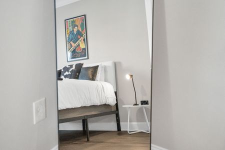 Bold artwork & a bright floor lamp give this bedroom a warm, curated vibe.