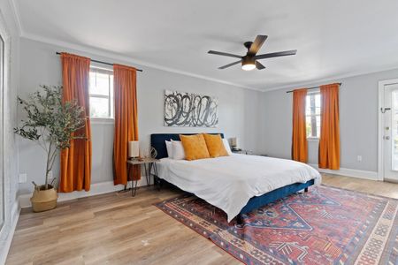 Bright master bedroom w/ bold orange curtains, attached bathroom & comfortable bed.