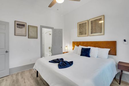 Airy bedroom w/ white walls, a classic bed frame, & soft natural light.