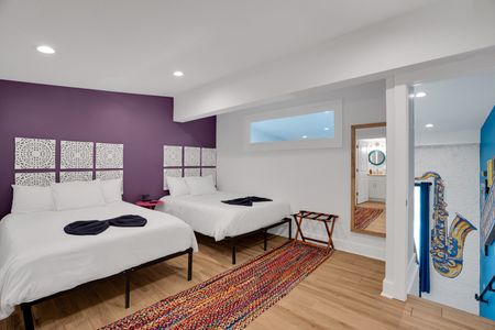 Bedroom 2 w/ twin beds, bold purple wall & a patterned rug for eclectic charm.