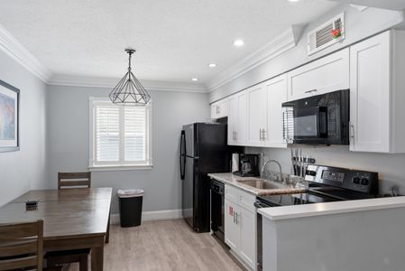 Sleek kitchen w/ black appliances — cook, dine & unwind in one space.
