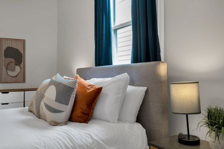 Bed dressed in layered pillows & warm tones for a snug, comfortable sleep.