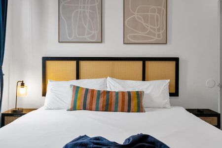 Bedroom w/ a woven headboard & striped pillows — relaxed & inviting.