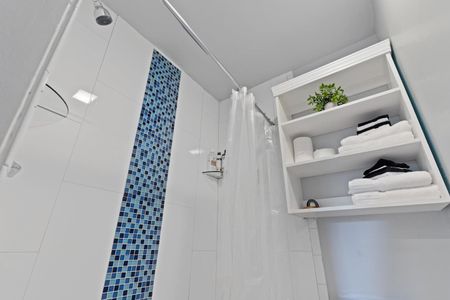 Second floor full bathroom w/ tiled shower & open shelving.