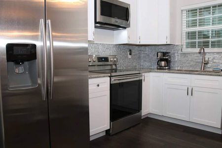 Sleek kitchen w/ stainless steel appliances & classic tile backsplash.