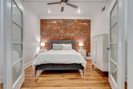 Airy bedroom w/ a queen bed nestled against charming exposed brick walls.