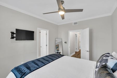 Airy bedroom w/ a wall-mounted TV & clean, minimal décor.