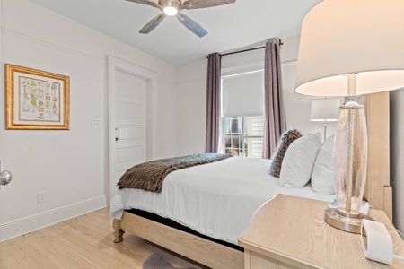 Bright primary bedroom w/ crisp white bedding & warm overhead lighting.
