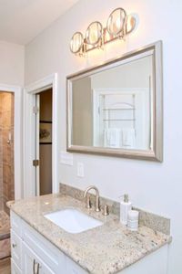 Bright bathroom w/ a framed mirror & warm wood-toned vanity.