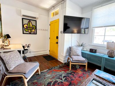 Eclectic living room w/ bold decor, a teal sofa & warm wood floors.