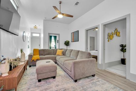 Bright living room w/ plush sofa, warm tones, & ceiling fan to kick back after a long day.