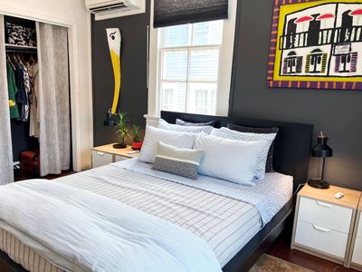Sun-drenched bedroom w/ a bed & natural light pouring through the windows.