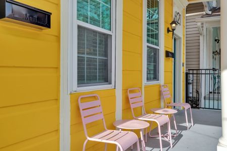 Sunny yellow exterior w/ a private patio & pink chairs — a cheerful spot to sip & unwind.
