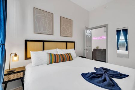 Cozy bedroom w/ bold black-frame bed, neon accent, & teal curtains adding personality.