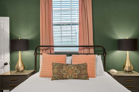 Cozy bed w/ soft peach & patterned bedding bathed in natural light.