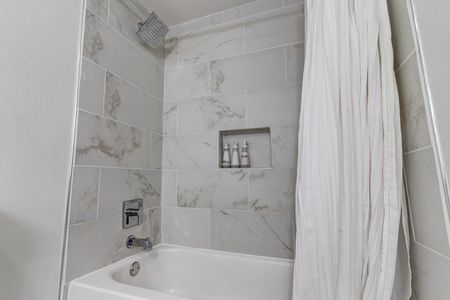 Tiled shower w/ sleek built-in niche — a refreshing start to any morning.