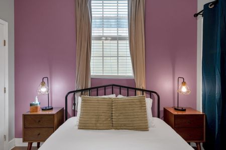 Bedroom w/ iron-frame bed & moody purple walls for a cozy, romantic feel.