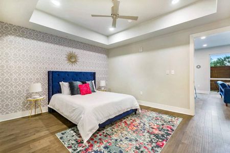 Bright bedroom w/ blue upholstered bed, bold floral bedding & ensuite access.