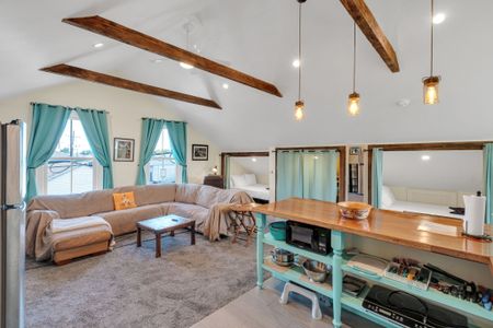 Airy living & dining area w/ exposed beams & warm, natural light.