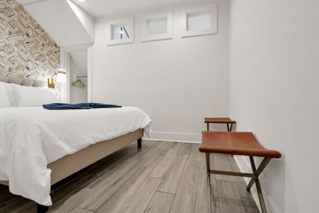 Spacious bedroom w/ warm wood tones, luxe textures & designer wallpaper.