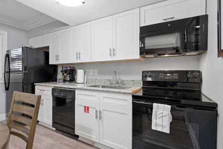 Cook with ease in a sleek kitchen w/ white cabinetry & black appliances.
