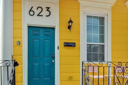 Vibrant teal front door w/ classic New Orleans yellow exterior — hard to miss & easy to love.