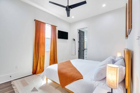 Bright bedroom w/ bold orange curtains & a warm, welcoming feel.