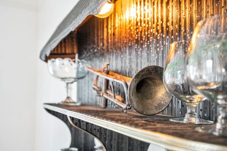 Dramatically styled bar shelf w/ vintage brass accents & moody lighting.