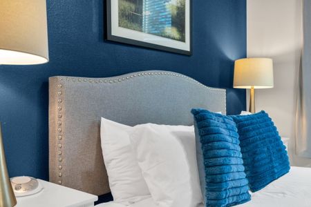 Plush bed w/ bold blue pillows & a tufted headboard for a boutique feel.