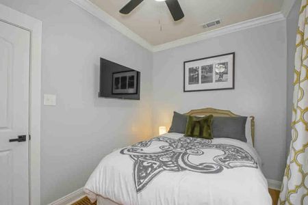 Charming bedroom w/ Fleur De Lis NOLA-themed décor, smart TV, & luggage rack.