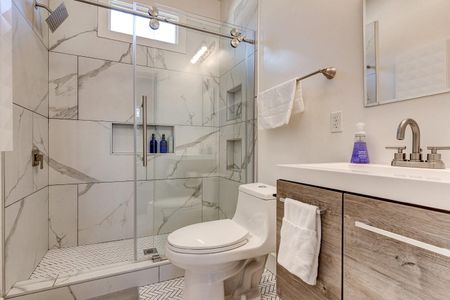 Sleek bathroom w/ marble-look tile, glass shower & modern vanity.