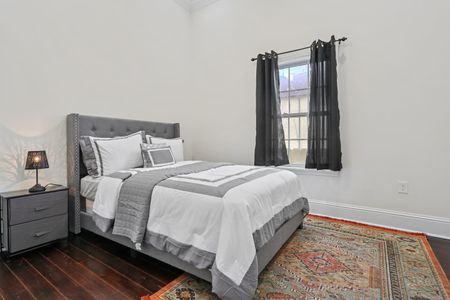 Cozy bedroom w/ a neatly made bed & natural light streaming through the curtains.