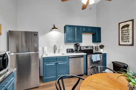 Teal cabinetry & stainless steel appliances in a well-equipped kitchen.